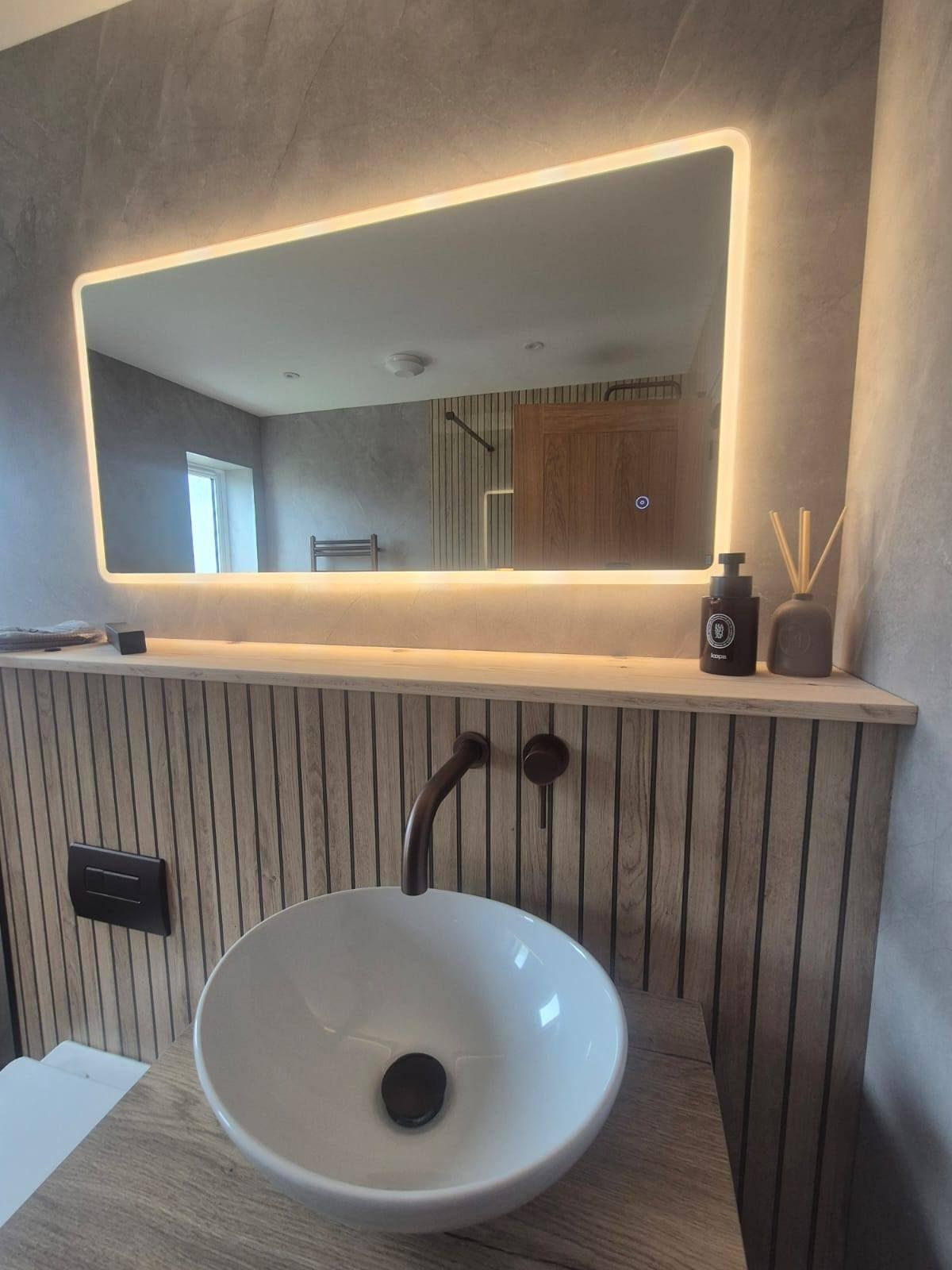 Designer bathroom vanity with backlit mirror and wood-slat wall