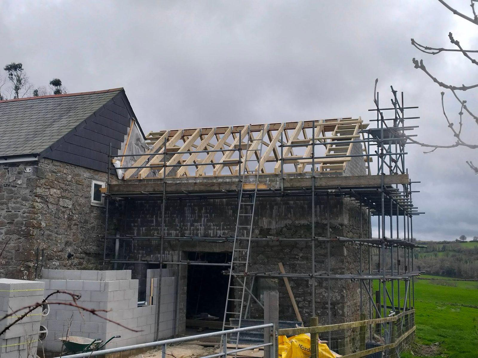 Stone barn house extension with new roof framing and scaffolding