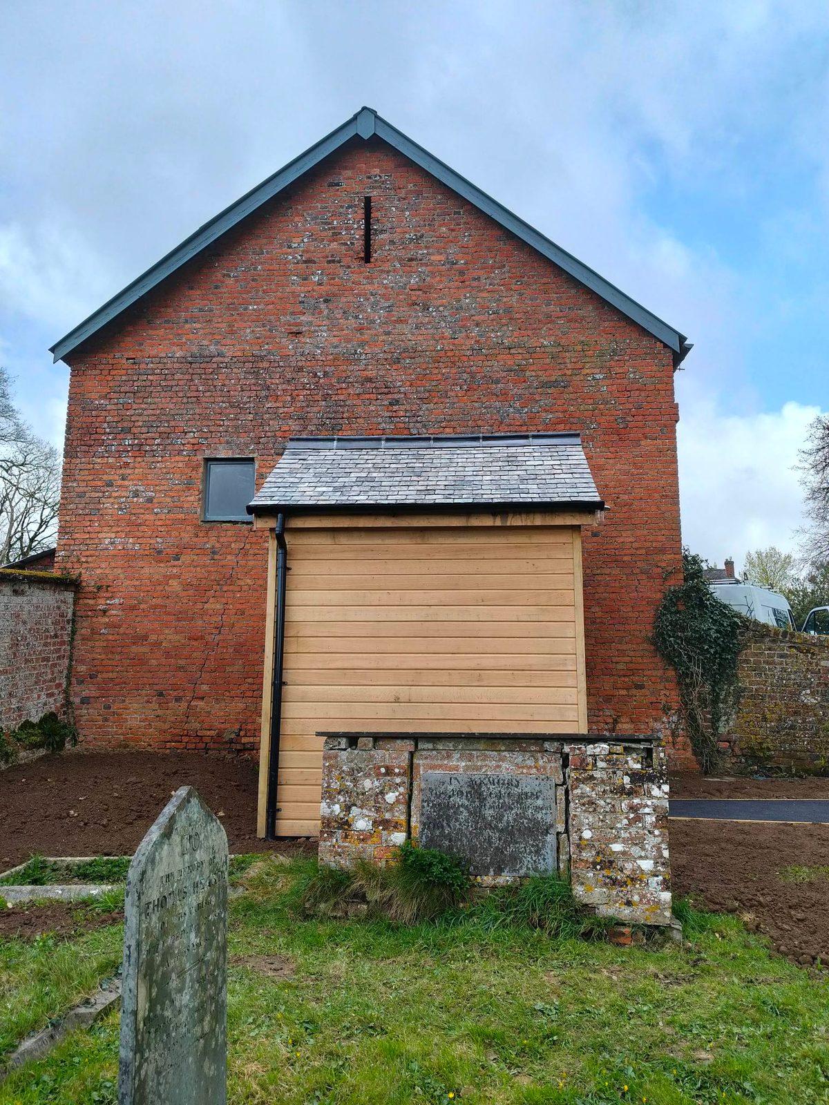 Timber-clad outbuilding extension against a brick gable