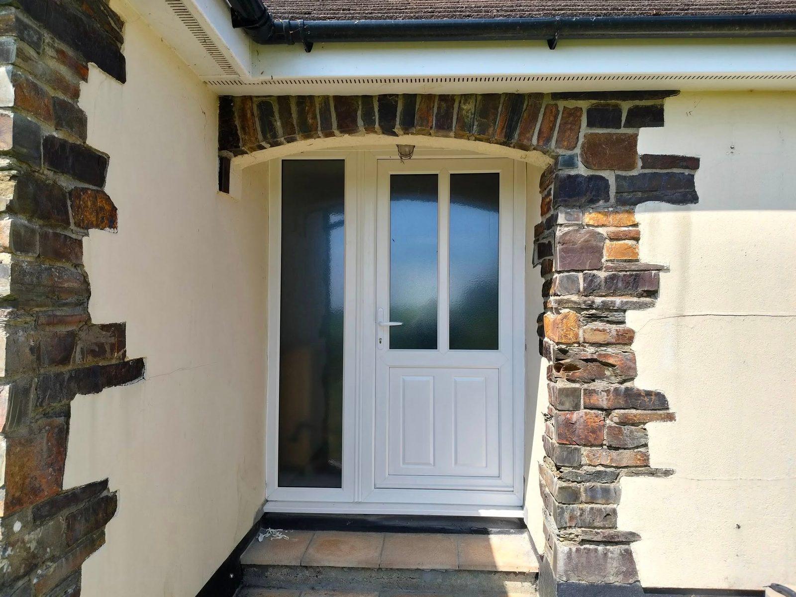 White uPVC front door set in a stone-arched porch