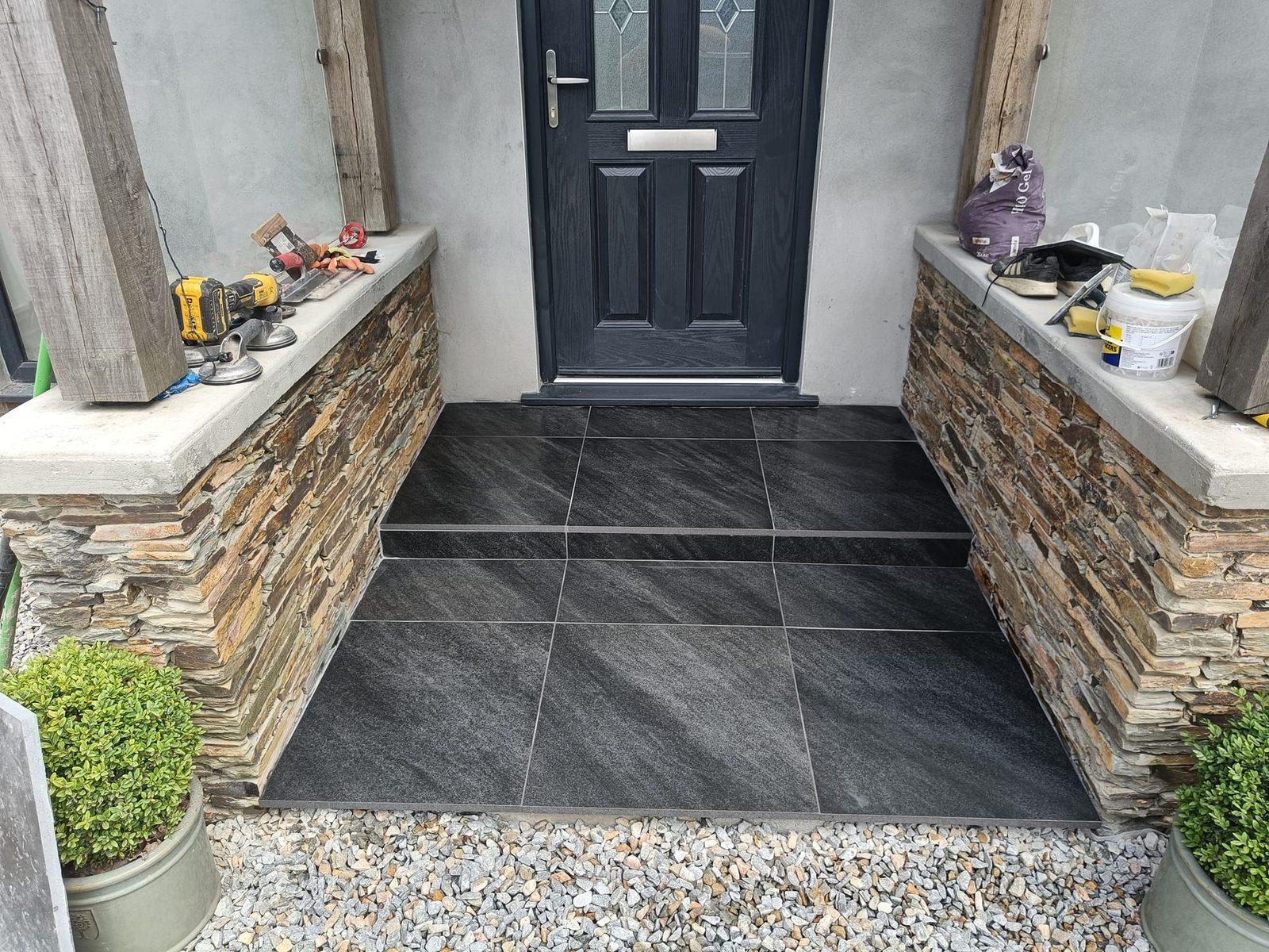 Finished slate-tiled porch with natural stone walls and composite door