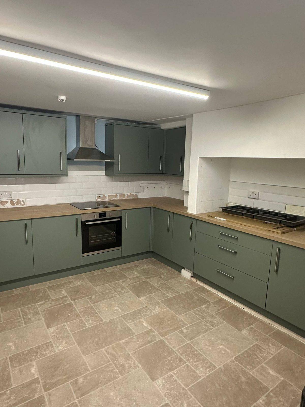 Sage-green L-shaped kitchen with oak worktops