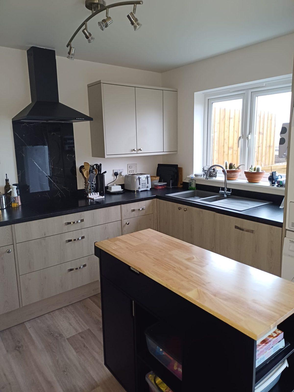 Modern kitchen installation with oak-effect units and marble splashback