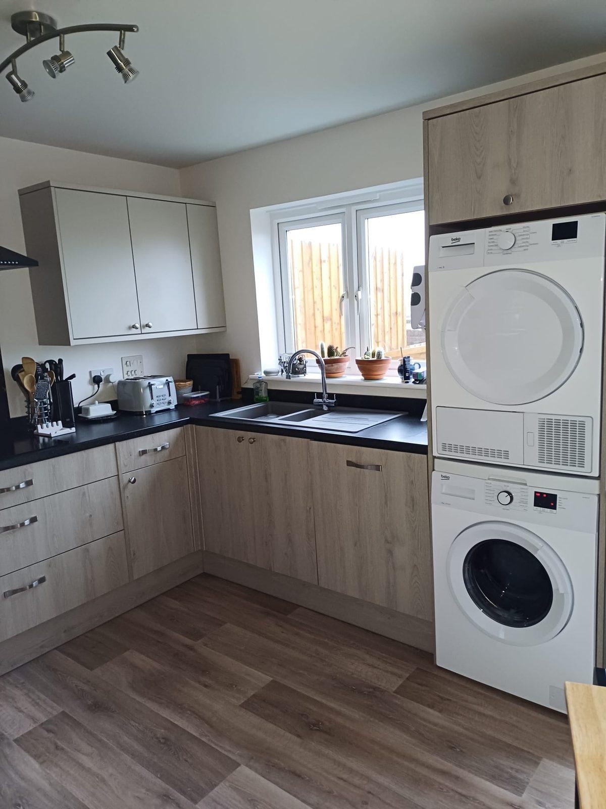 Kitchen with grey units and black worktop by the window
