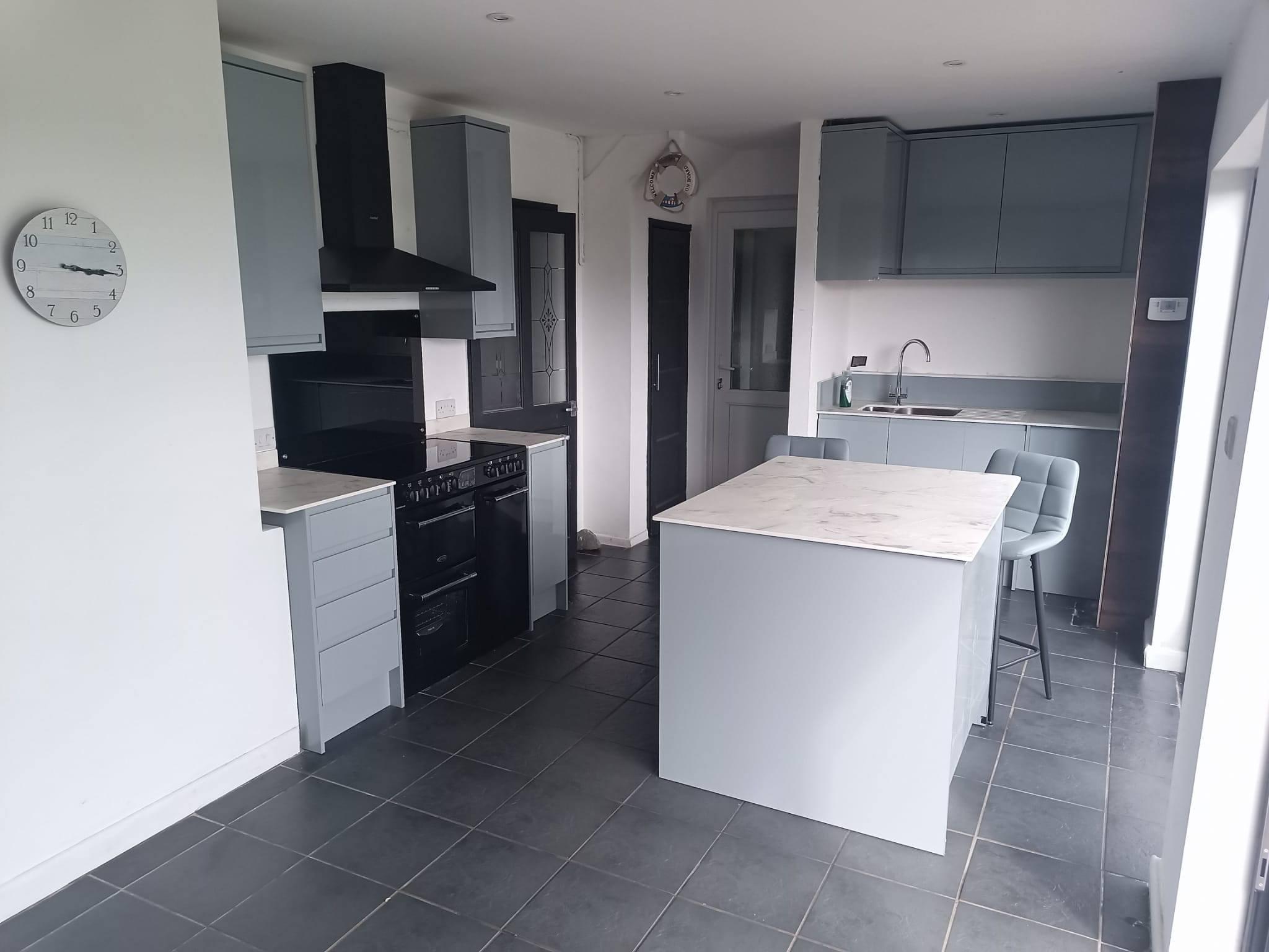 Open-plan grey shaker kitchen with marble-top island and range cooker