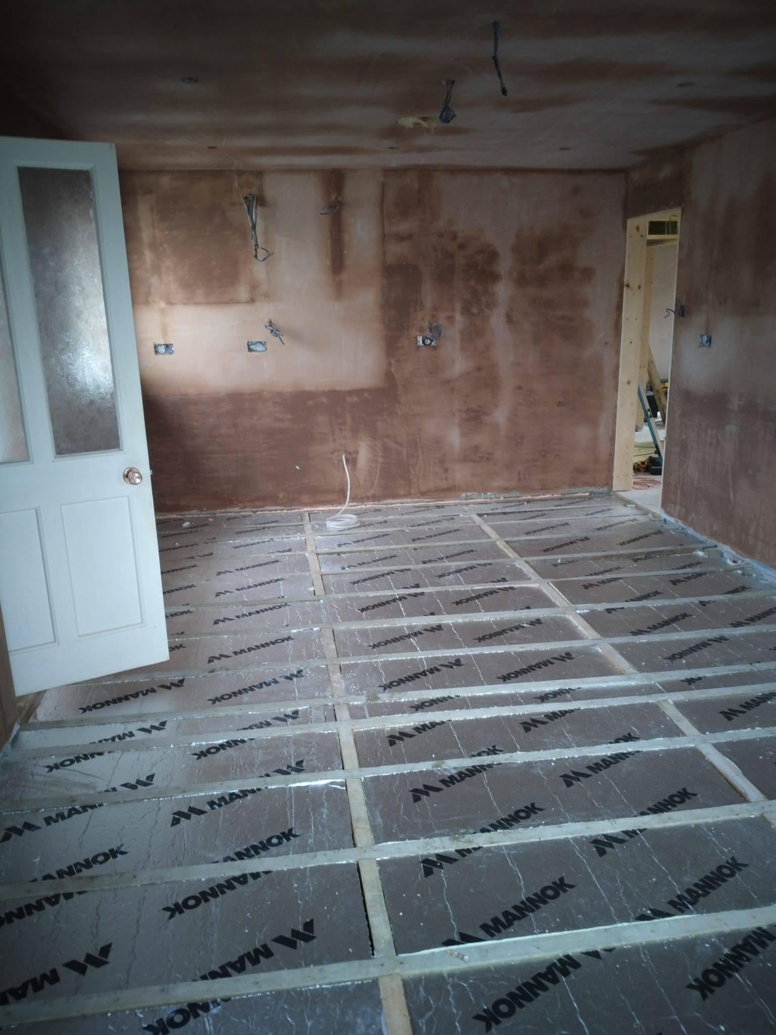 Stripped renovation room with fresh plaster and underfloor insulation in place