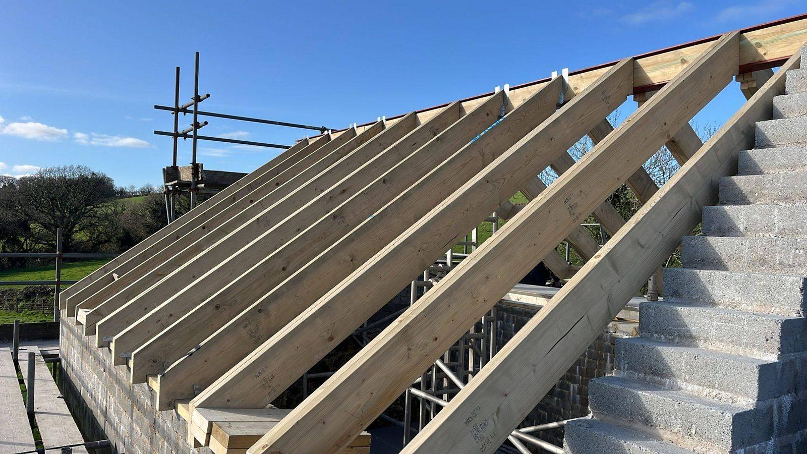 Fresh timber roof rafters against a clear blue sky