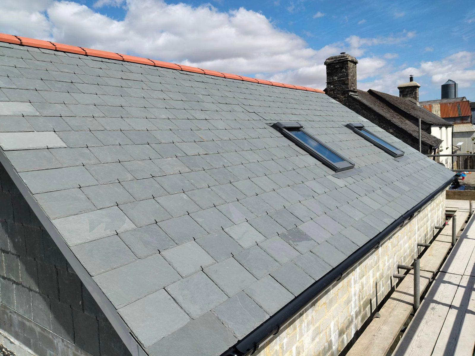 Completed slate roof with rooflights against a bright sky