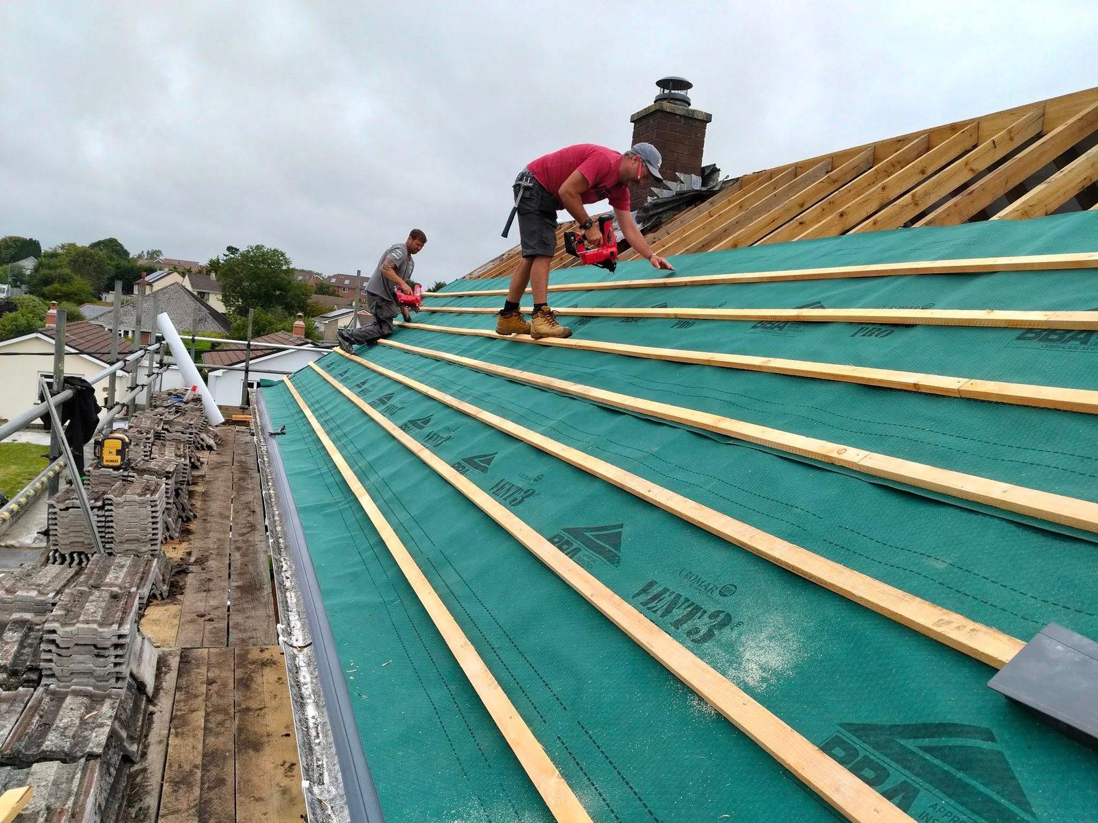Roofers laying breathable membrane and battens during a re-roof